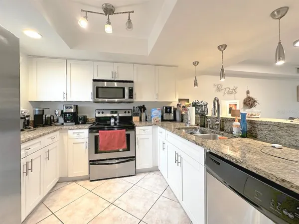a kitchen with granite countertop a stove top oven a sink a counter space and cabinets
