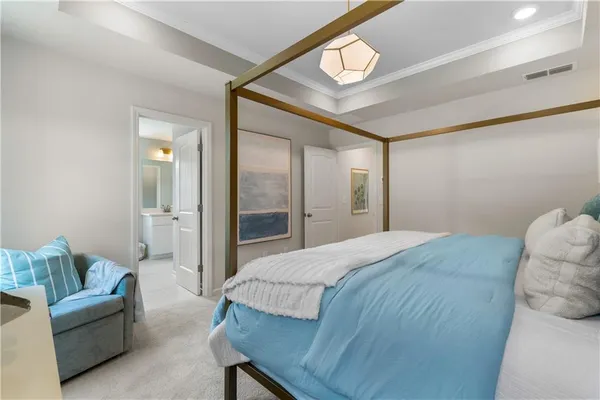 a bedroom with a bed a mirror on the dresser and chandelier