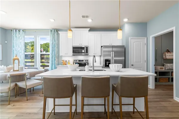 a kitchen with stainless steel appliances granite countertop a stove a sink a microwave a dining table and chairs with wooden floor