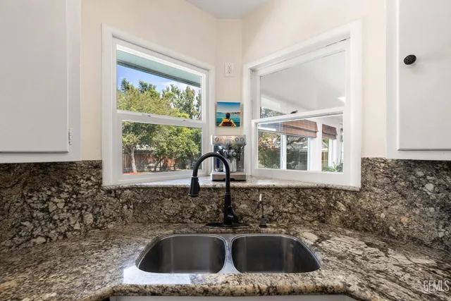 a kitchen with granite countertop white cabinets stainless steel appliances and a counter space