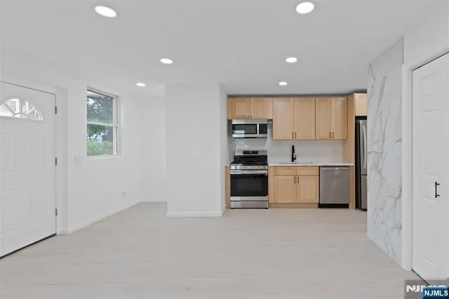 a kitchen with stainless steel appliances a refrigerator and white cabinets