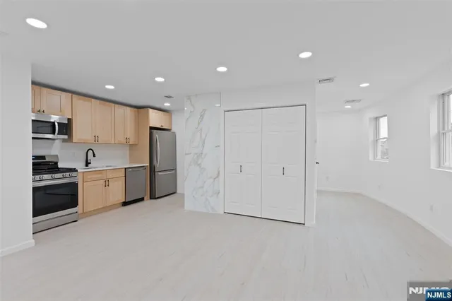 a large kitchen with a large white kitchen island a sink stainless steel appliances and cabinets