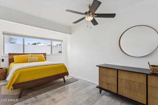 a bedroom with a bed a mirror and a lamp on dresser