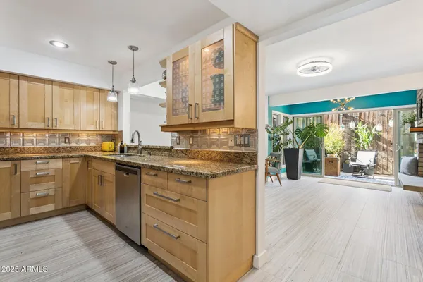 a kitchen with granite countertop a stove a sink and white cabinets with wooden floor