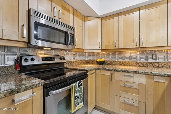a kitchen with granite countertop a stove sink and microwave