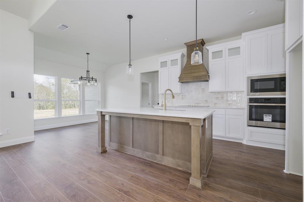 1844 County Road 2320 Terrell, TX 75160 - Photo 19 of 27 a kitchen with stainless steel appliances granite countertop a sink a microwave oven a refrigerator and white cabinets with wooden floor