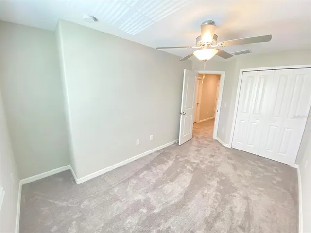 a view of an empty room with a chandelier fan