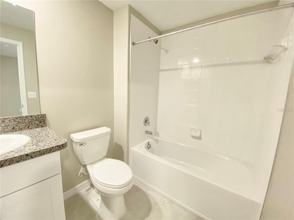 3523 Bellmeade Court Wesley Chapel, FL 33543 - Photo 13 of 22 a bathroom with a granite countertop toilet a sink and a bathtub