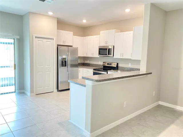 a kitchen with stainless steel appliances granite countertop a refrigerator a stove a sink and a refrigerator