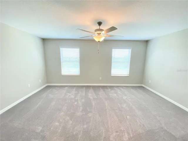 an empty room with windows and fan