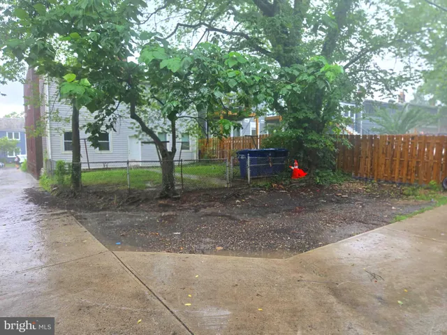 a view of road with large trees and wooden fence