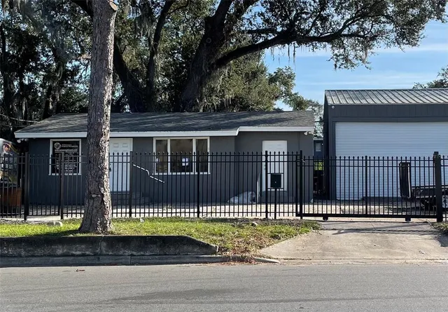 a front view of a house with a garden and large trees