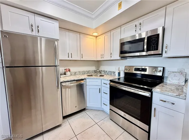 a kitchen with stainless steel appliances white cabinets white stove a microwave and a refrigerator
