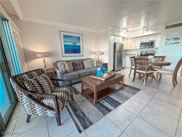 a living room with furniture a rug and kitchen view