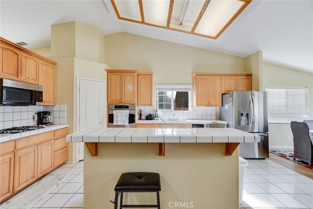12794 Rain Shadow Road Victorville, CA 92395 - Photo 14 of 50 a large kitchen with kitchen island granite countertop a stove a sink dishwasher and a refrigerator