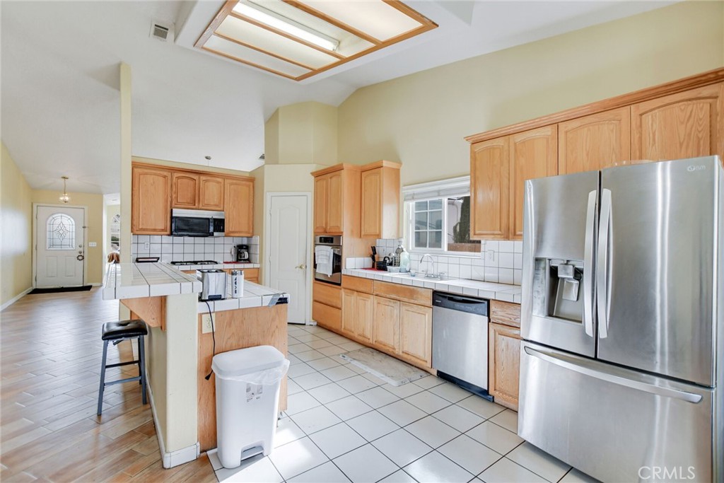 12794 Rain Shadow Road Victorville, CA 92395 - Photo 15 of 50 a kitchen with stainless steel appliances granite countertop a refrigerator a stove a sink a dining table and chairs with wooden floor