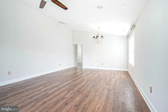 an empty room with wooden floor cabinet and windows