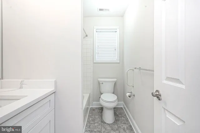 a bathroom with a granite countertop toilet and sink