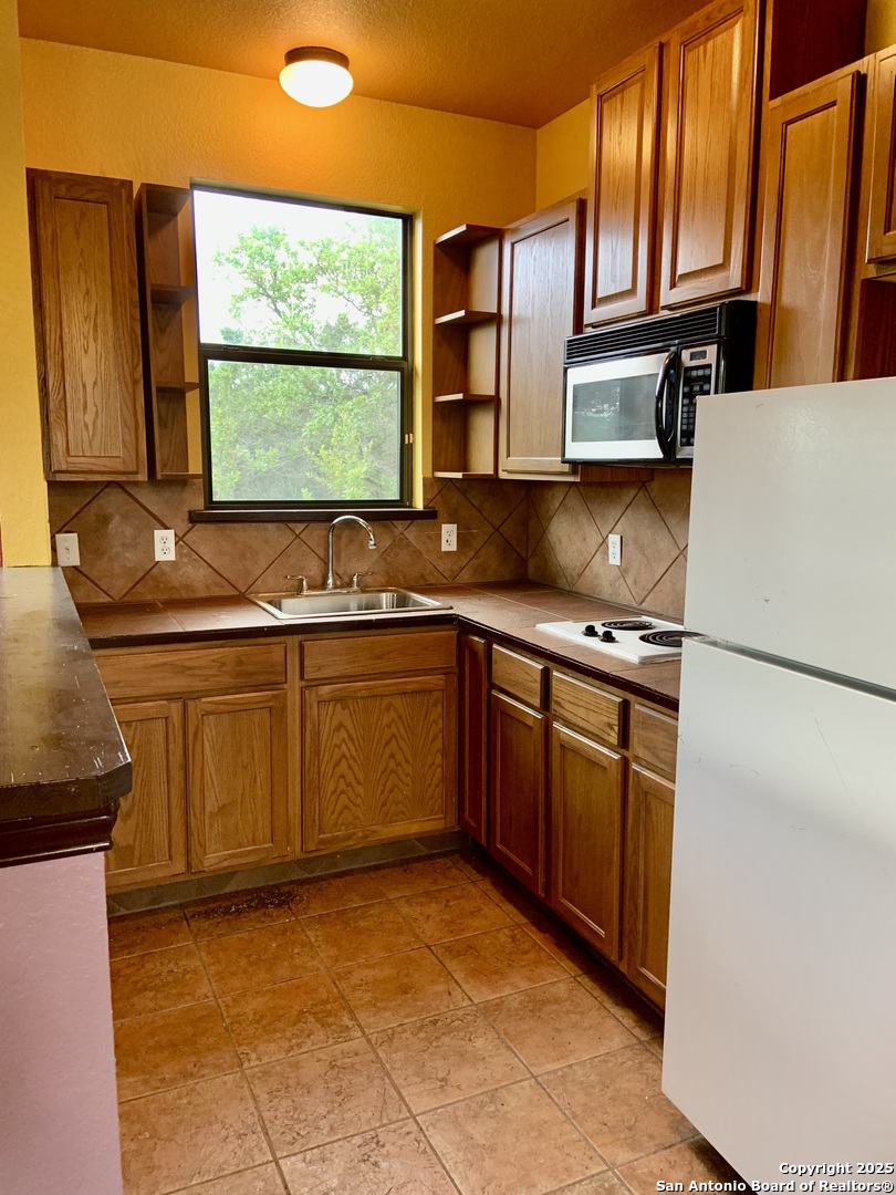19940 Scenic Loop Road San Antonio, TX 78255 - Photo 25 of 34 a kitchen with stainless steel appliances granite countertop a sink and a refrigerator