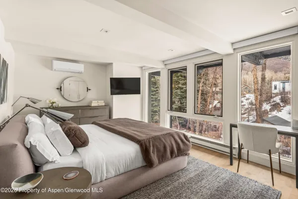 a bedroom with a bed a mirror and a large window