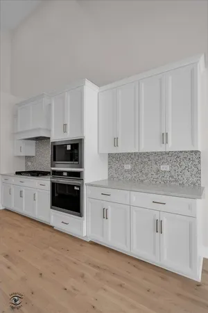 a kitchen with granite countertop white cabinets and stainless steel appliances
