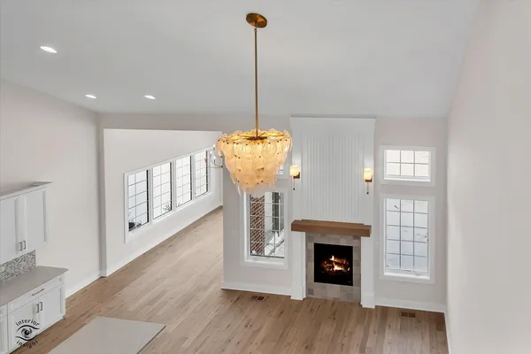 a view of an empty room with wooden floor fireplace and a window