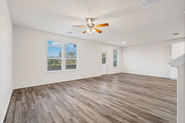 a view of empty room with wooden floor and ceiling fan