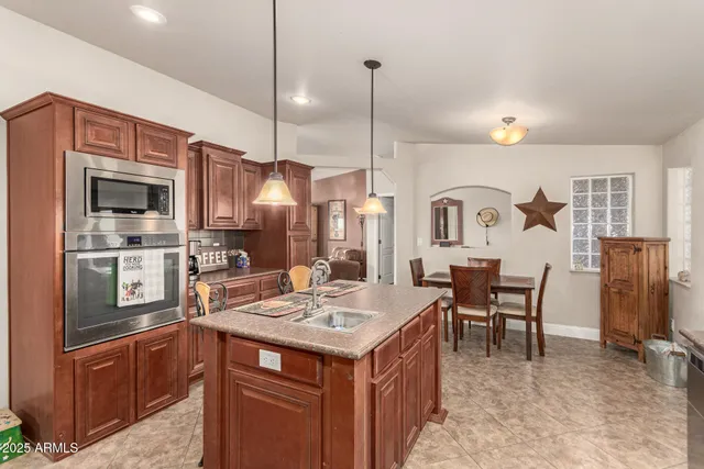 a kitchen with a refrigerator a stove top oven a sink dishwasher and couches with wooden floor