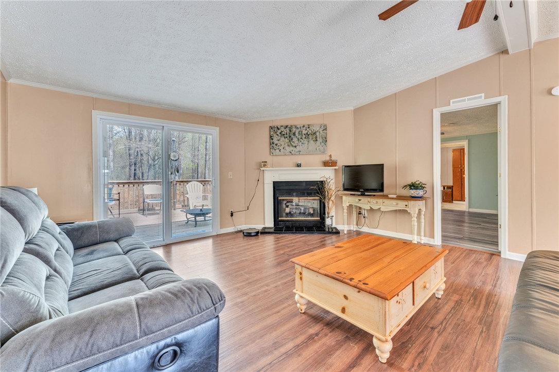 137 East Reedy Fork Road Seneca, SC 29678 - Photo 11 of 28 This inviting living space features warm flooring, a cozy fireplace, and direct access to an outdoor deck.
