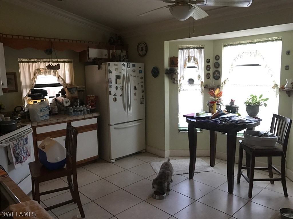 2590 54th Street Southwest Naples, FL 34116 - Photo 2 of 6 a kitchen with a refrigerator a table chairs and a refrigerator