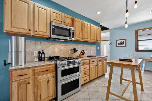 a kitchen with stainless steel appliances granite countertop a stove top oven a sink dishwasher and white cabinets with wooden floor