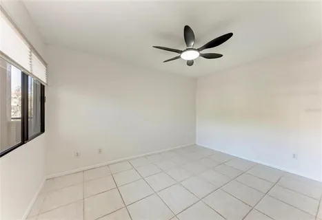an empty room with ceiling fan and window