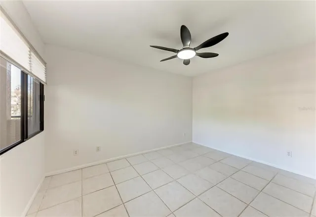 an empty room with ceiling fan and window