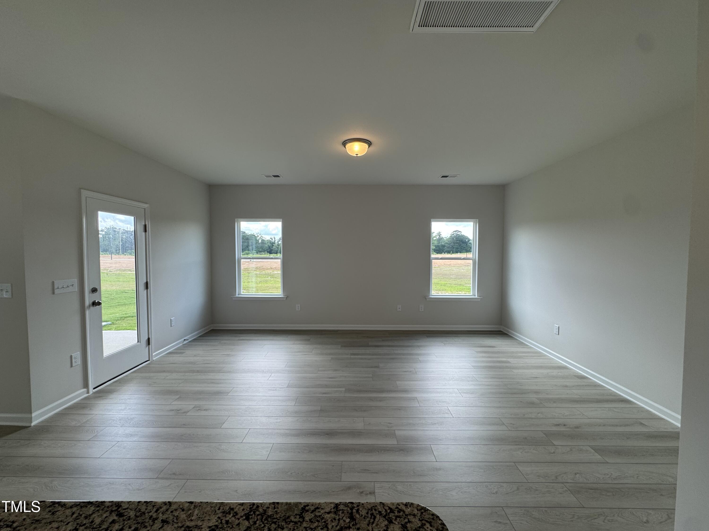 184 Bruce Drive Dunn, NC 28334 - Photo 4 of 32 an empty room with wooden floor and windows
