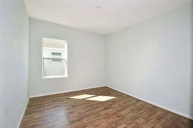 an empty room with wooden floor and window