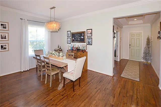 a dining room with wooden floor a chandelier a wooden table and chairs