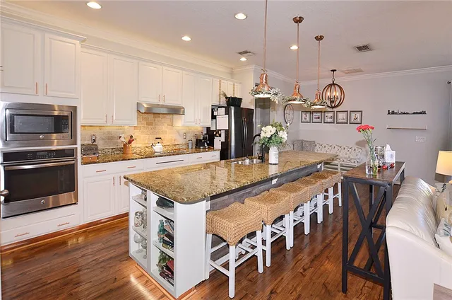 a kitchen with stainless steel appliances granite countertop a kitchen island a stove a table and chairs