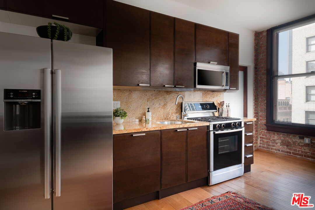 460 South Spring Street, Unit 1015 Los Angeles, CA 90013 - Photo 6 of 50 a kitchen with stainless steel appliances granite countertop a refrigerator a stove a sink and a microwave