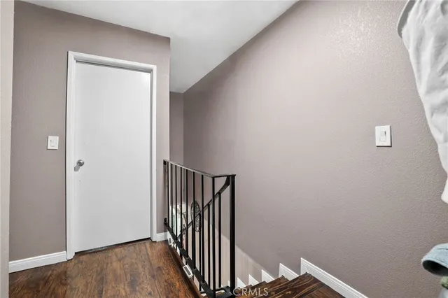 a view of a hallway with wooden floor and a bathroom