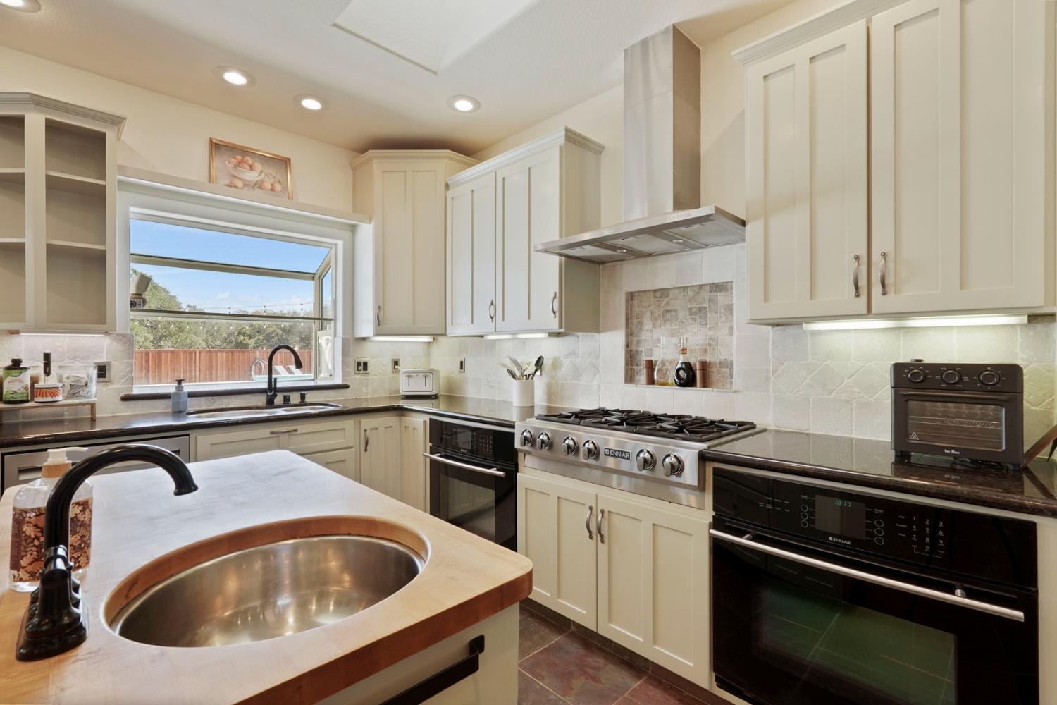 8779 Ospital Road Valley Springs, CA 95252 - Photo 39 of 80 a kitchen with granite countertop white cabinets and stainless steel appliances
