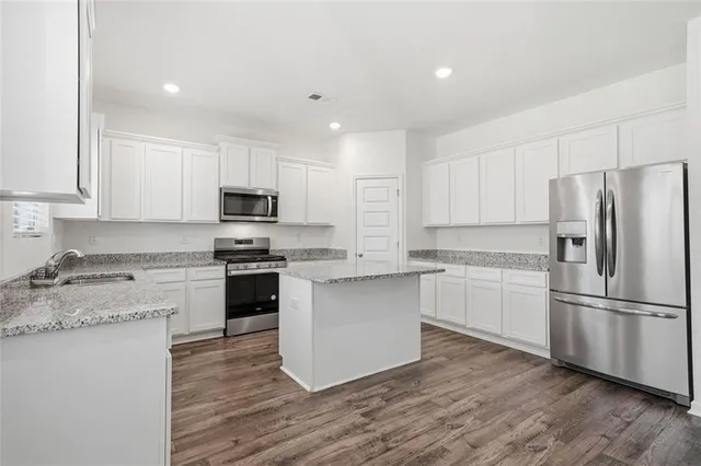 a kitchen with granite countertop white cabinets and stainless steel appliances