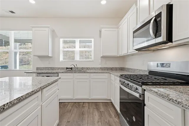 a kitchen with stainless steel appliances granite countertop a stove and a microwave