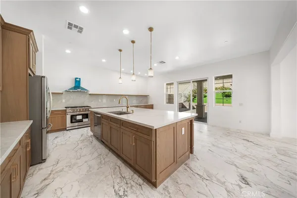 a large kitchen with kitchen island a sink a counter top stainless steel appliances and cabinets