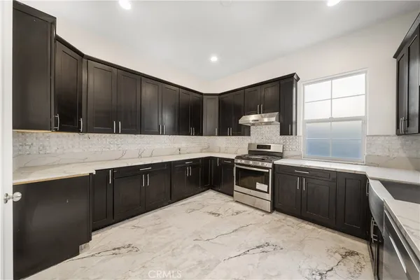 a large kitchen with stainless steel appliances kitchen island granite countertop a refrigerator and a sink