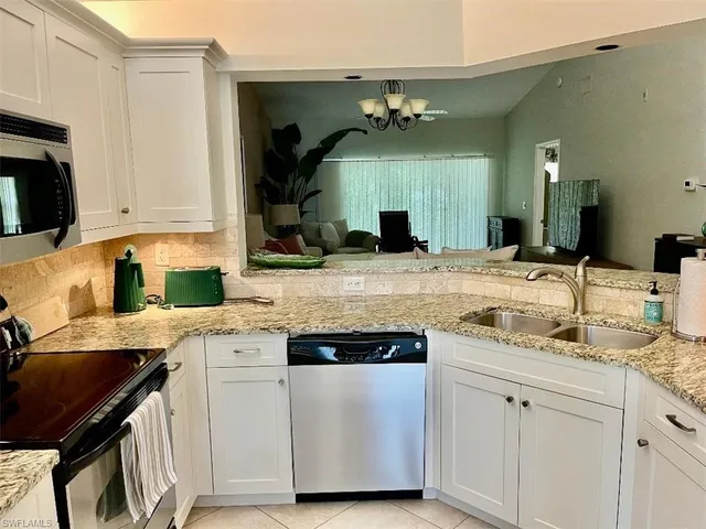 a kitchen with a sink dishwasher a stove and white cabinets