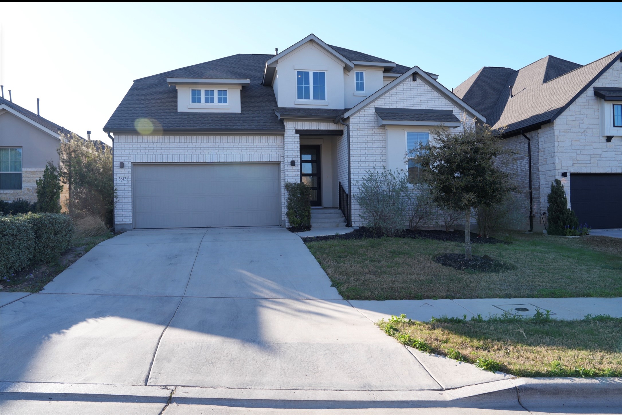 View of front of home featuring concrete driveway, brick siding, a front yard, and a shingled roof