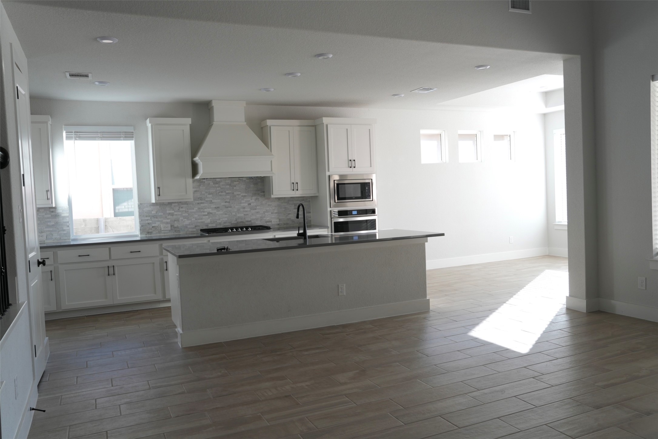 3812 Mercer Road Georgetown, TX 78628 - Photo 6 of 33 Kitchen with white cabinetry, an island with sink, wood tiled floors, and recessed lighting
