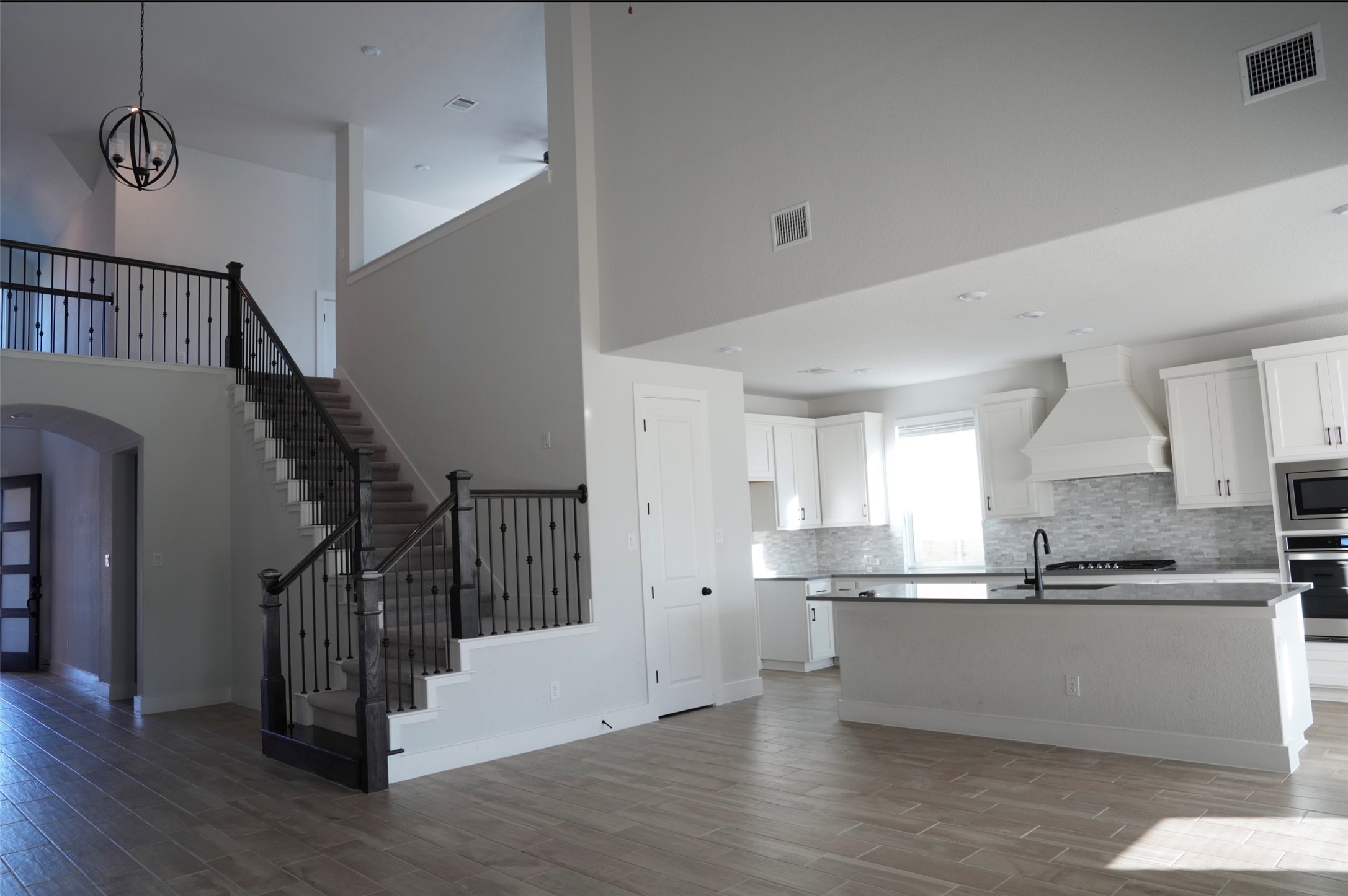 3812 Mercer Road Georgetown, TX 78628 - Photo 8 of 33 Kitchen with white cabinets, a center island with sink, dark wood-type flooring, arched walkways, and stainless steel appliances