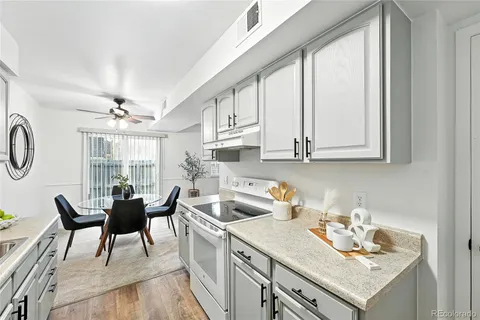 a kitchen with stainless steel appliances granite countertop a stove a sink dishwasher and white cabinets with wooden floor