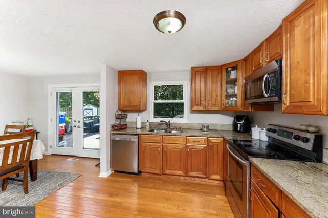 a kitchen with stainless steel appliances granite countertop a sink dishwasher stove top oven and wooden cabinets